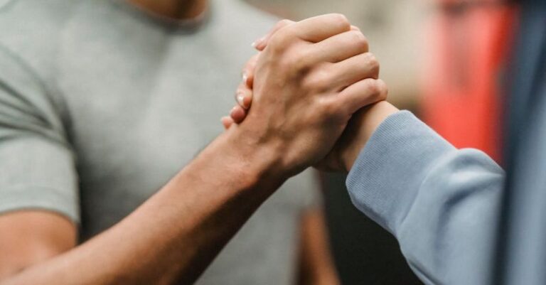 Techniques - Crop sportive couple clasping hands in gym