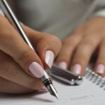 Schedule - Woman in White Long Sleeved Shirt Holding a Pen Writing on a Paper