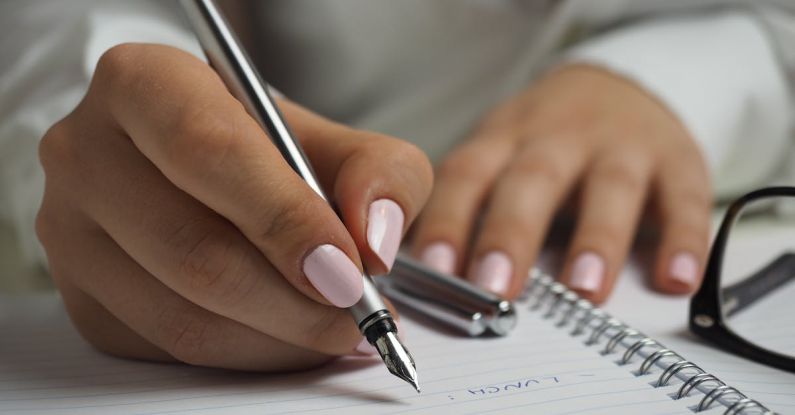 Schedule - Woman in White Long Sleeved Shirt Holding a Pen Writing on a Paper