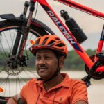 Routine - Photo of Man Wearing Orange Polo Shirt Sitting Beside His Bike