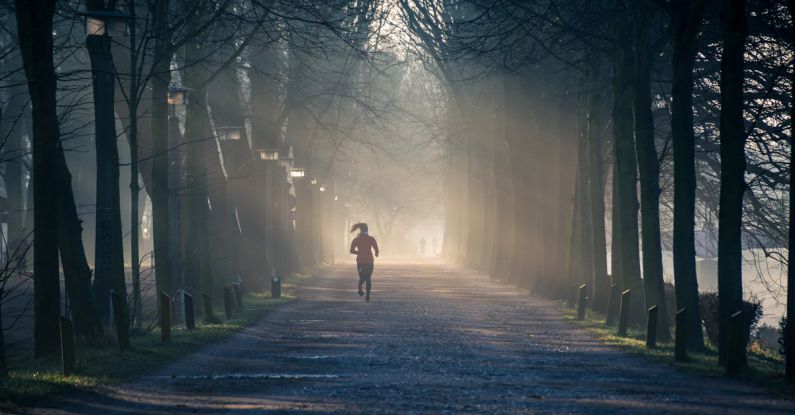 Exercise - Person Running Near Street Between Tall Trees