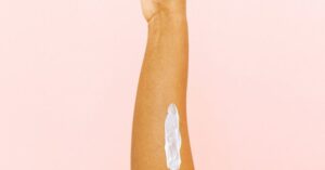 Therapy - Female arm with smear for skin care against pink background