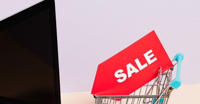 Reduction - A Red Sale Tag on a Miniature Shopping Cart Placed on a Macbook Laptop