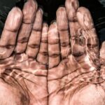 Routine - From above of crop anonymous male washing hands in clean water of lake in daytime