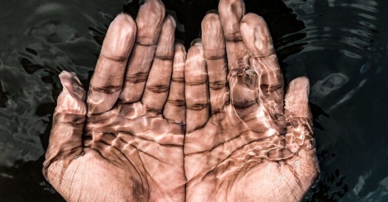 Routine - From above of crop anonymous male washing hands in clean water of lake in daytime